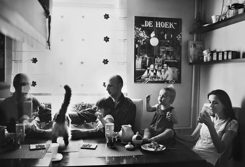 Klaipėdiečių Giedrės ir Andriaus šeimos pusryčiai namų virtuvėje. Gausi šeima, katinas, žuvų akvariumo stiklo atspindžiai, vaišės ant stalo, prieskoniai lentynėlėse. Ant sienos - vestuvinis pusryčiaujančių jaunavedžių portretas, kas rytą liudijantis augančios šeimos pusryčių ritualus.